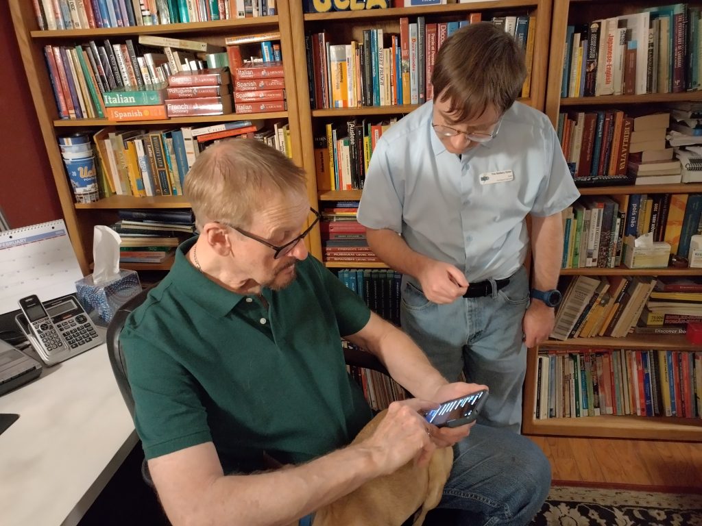 technician helping a senior with his smartphone at his home